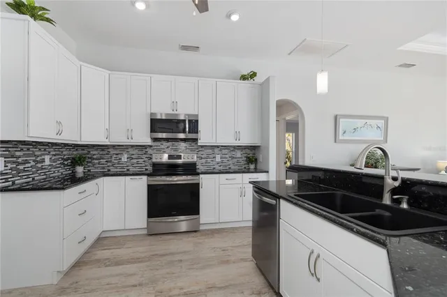 a kitchen with granite countertop white cabinets and stainless steel appliances