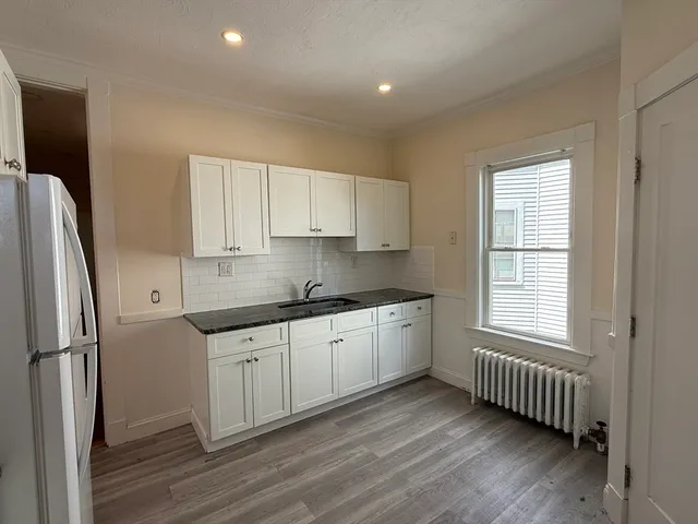 a kitchen with stainless steel appliances granite countertop a refrigerator sink and white cabinets