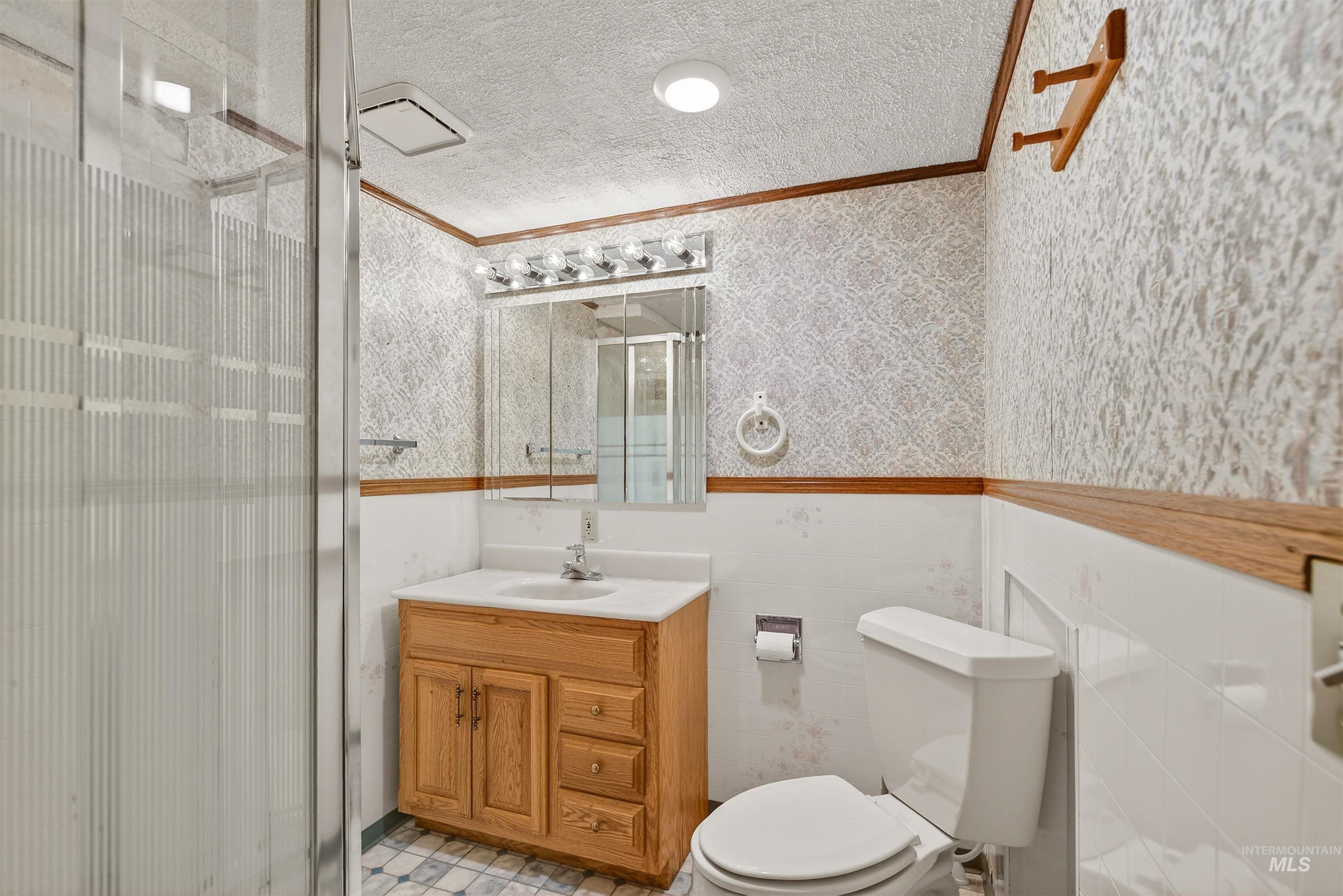 209 Walnut Drive Potlatch, ID 83855 - Photo 18 of 27 Full bath featuring a shower stall, vanity, a textured ceiling, crown molding, and a wainscoted wall