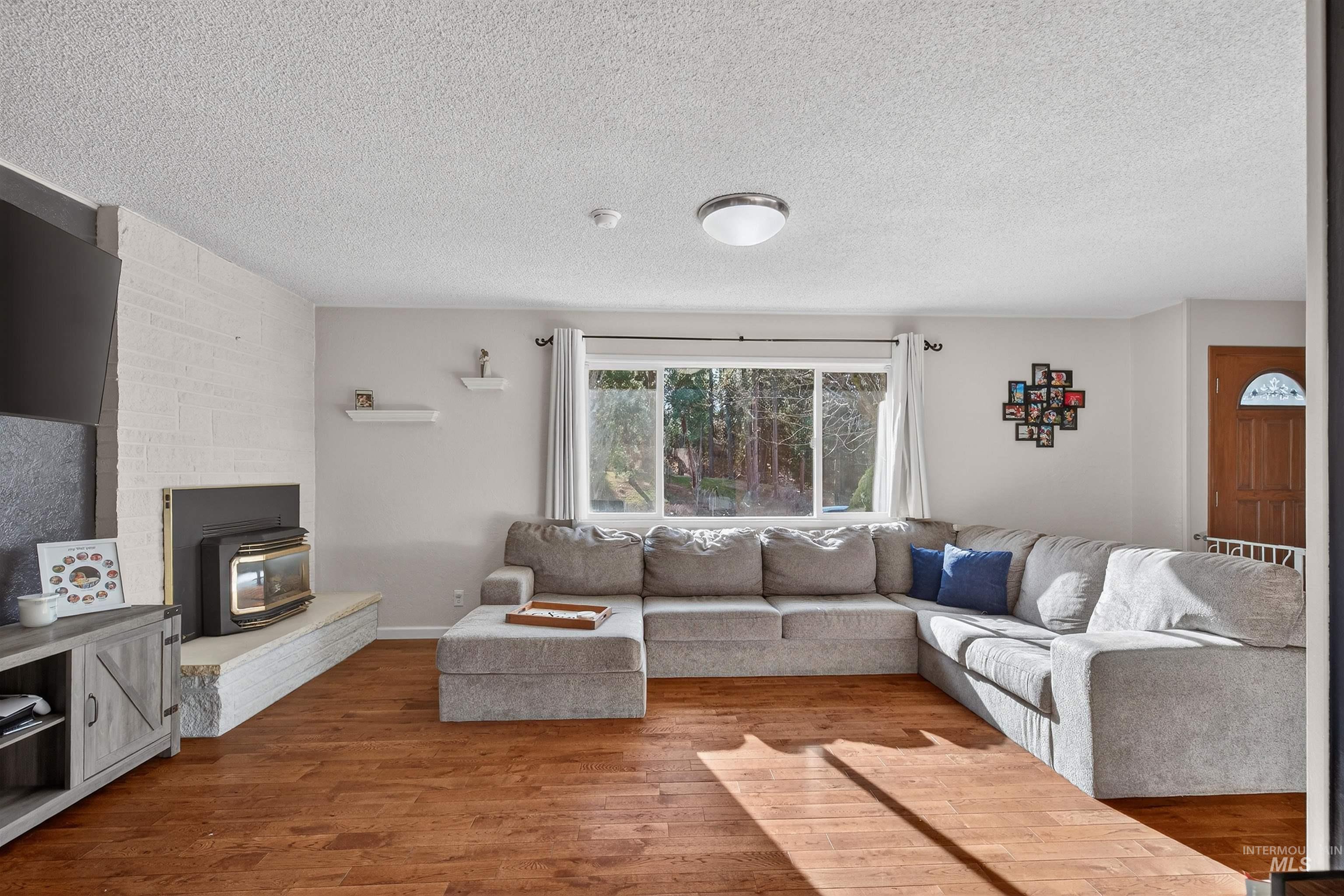 209 Walnut Drive Potlatch, ID 83855 - Photo 4 of 27 Living room with a wood stove, wood finished floors, and a textured ceiling