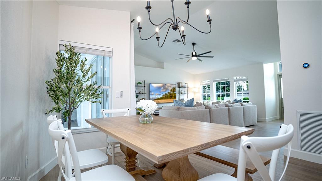 9151 Irving Road Fort Myers, FL 33967 - Photo 32 of 44 Dining area with wood finished floors, a chandelier, ceiling fan, and high vaulted ceiling