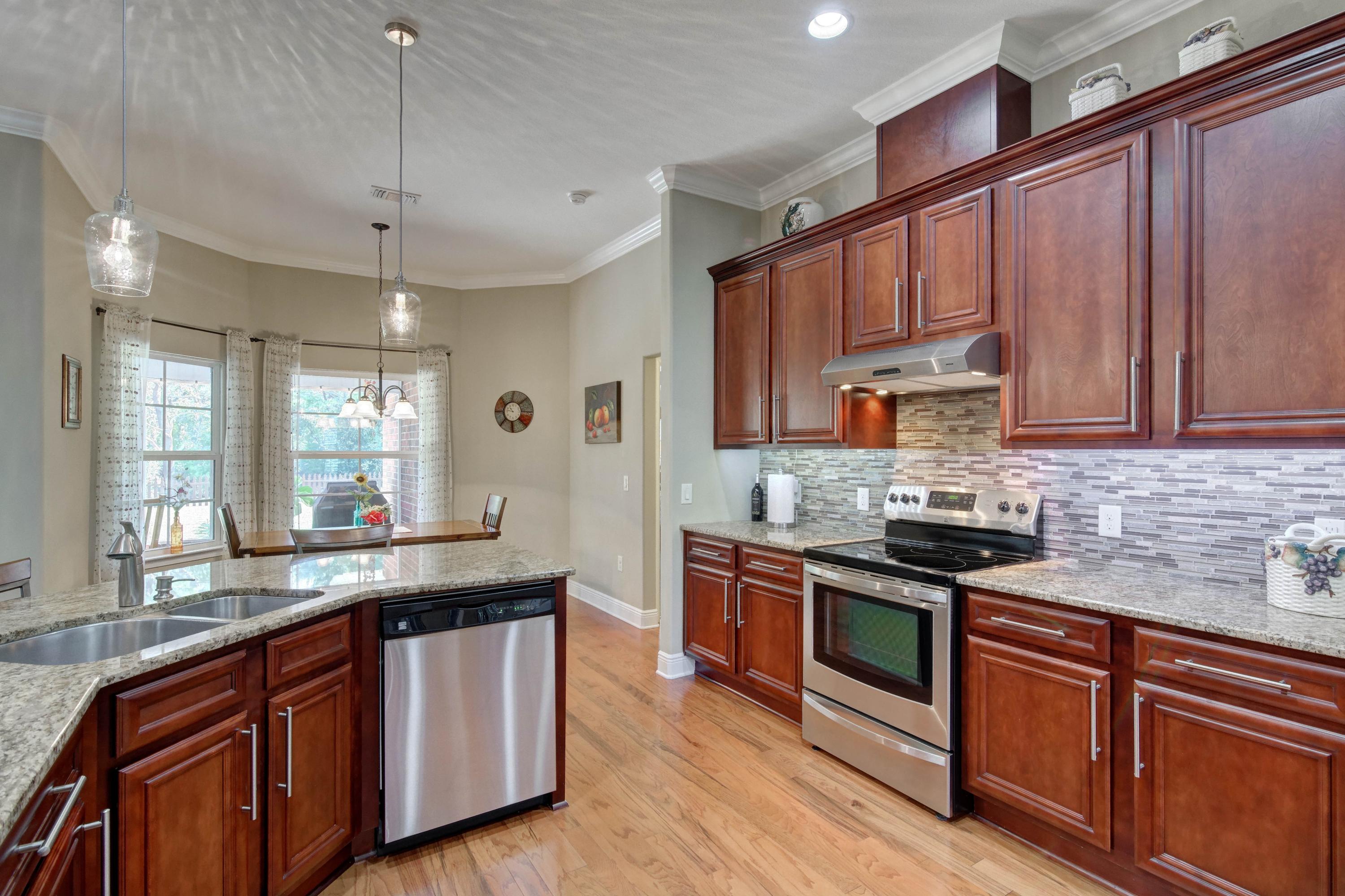 2592 Crescent Road Navarre, FL 32566 - Photo 21 of 67 a kitchen with stainless steel appliances granite countertop wooden cabinets a sink a stove a refrigerator and island with wooden floors