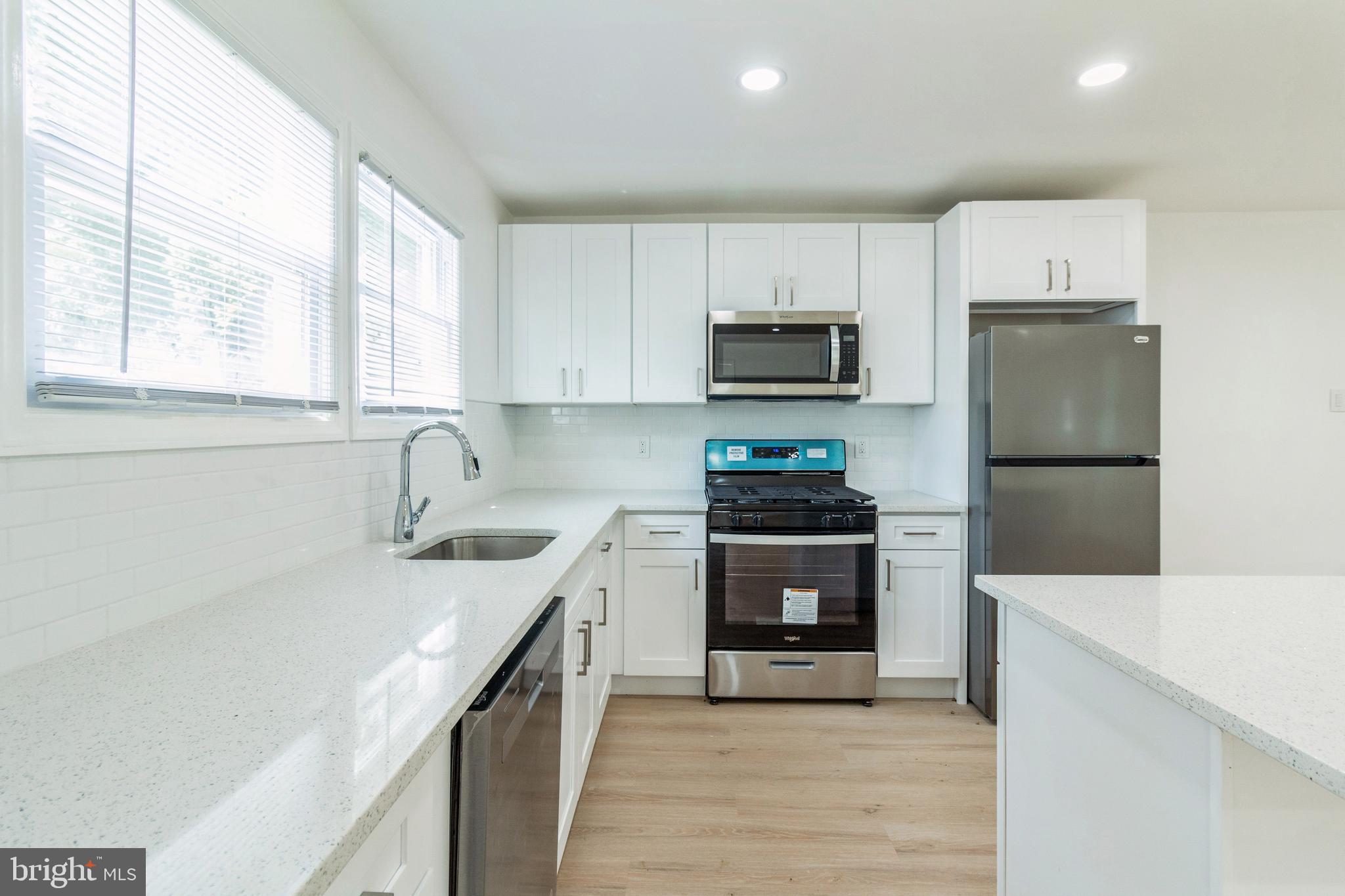 a kitchen with stainless steel appliances a sink cabinets and a window