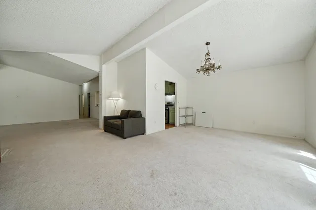 a view of a livingroom with a fireplace a chandelier and windows