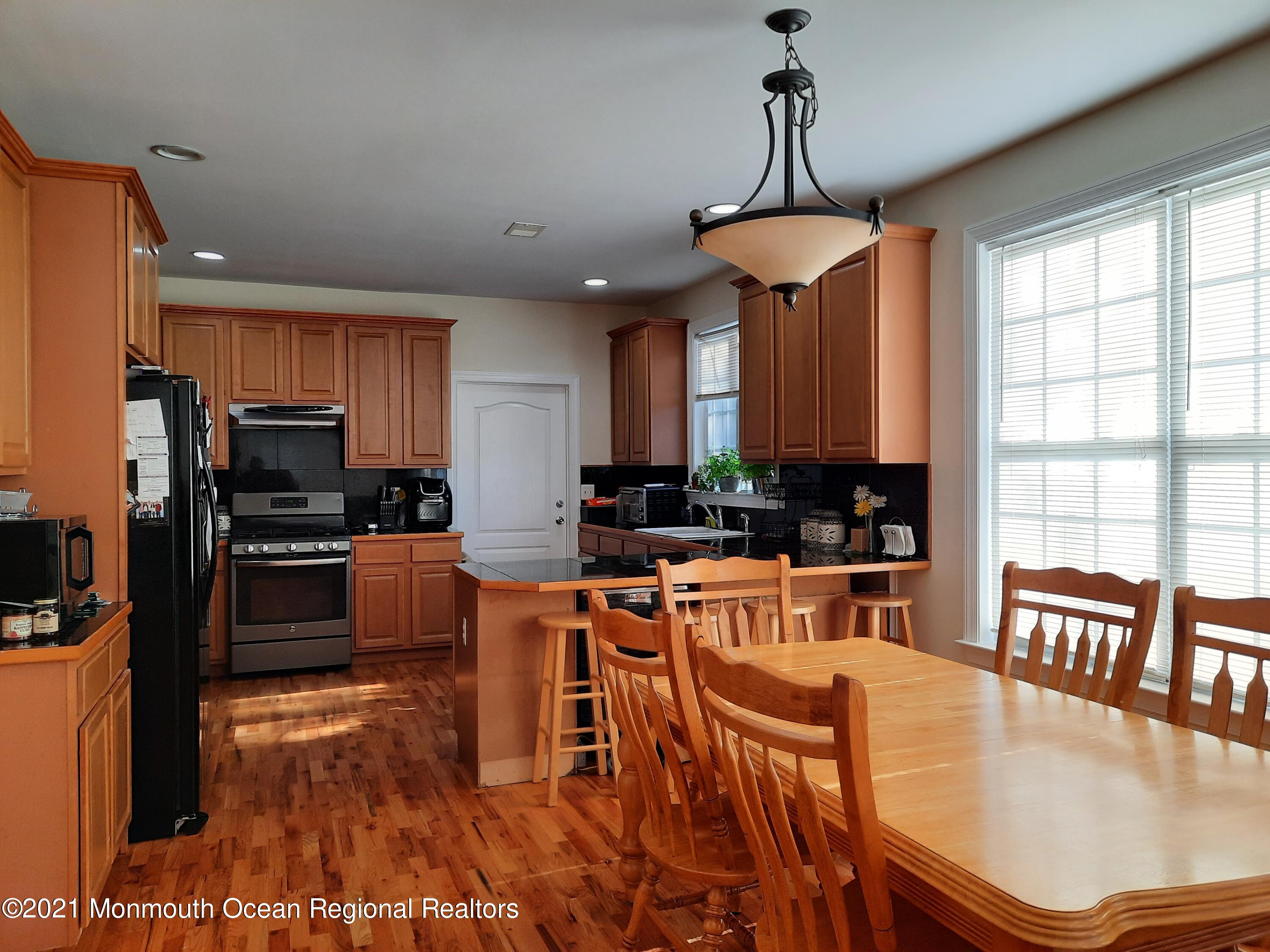 607 Dave Marion Road Toms River, NJ 08753 - Photo 3 of 9 a kitchen with stainless steel appliances granite countertop a stove top oven a refrigerator a dining table and chairs with wooden floor