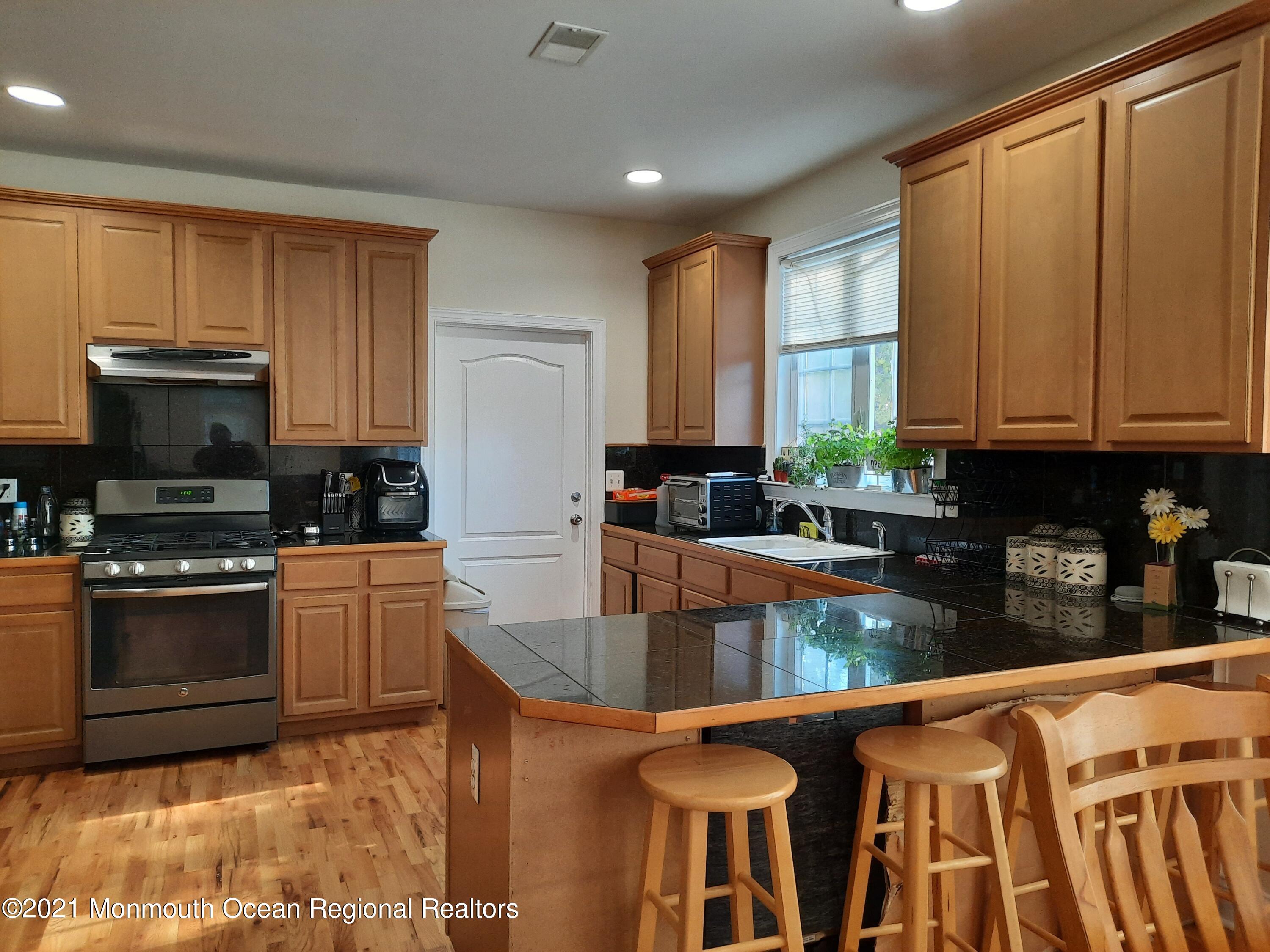 607 Dave Marion Road Toms River, NJ 08753 - Photo 5 of 9 a kitchen with stainless steel appliances granite countertop a stove top oven a sink a dining table and chairs