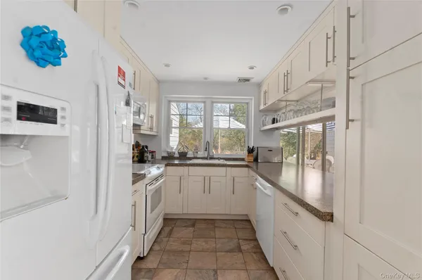 a large white kitchen with stainless steel appliances granite countertop a refrigerator and a sink