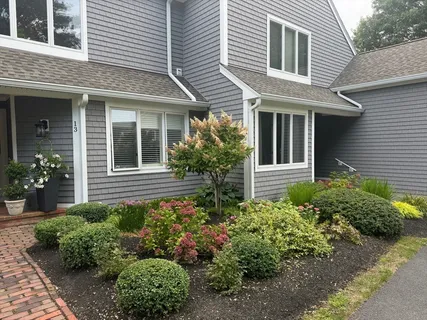 a view of a house with potted plants and a flower garden
