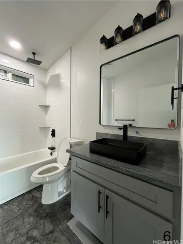 a bathroom with a granite countertop sink a toilet a mirror and bathtub