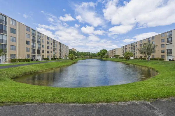 a view of a lake with a big yard and large trees