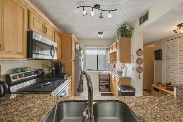 a kitchen with stainless steel appliances granite countertop a sink dishwasher and cabinets with wooden floor