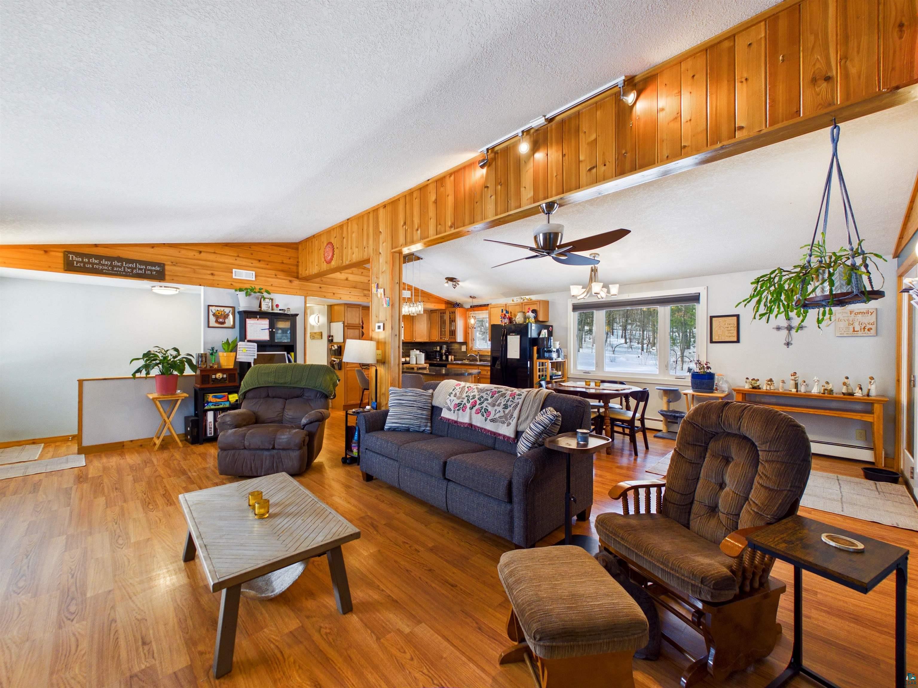10719 North Oak Ridge Street Hayward, WI 54843 - Photo 12 of 57 Living area featuring a ceiling fan, wood finished floors, baseboard heating, and wooden walls