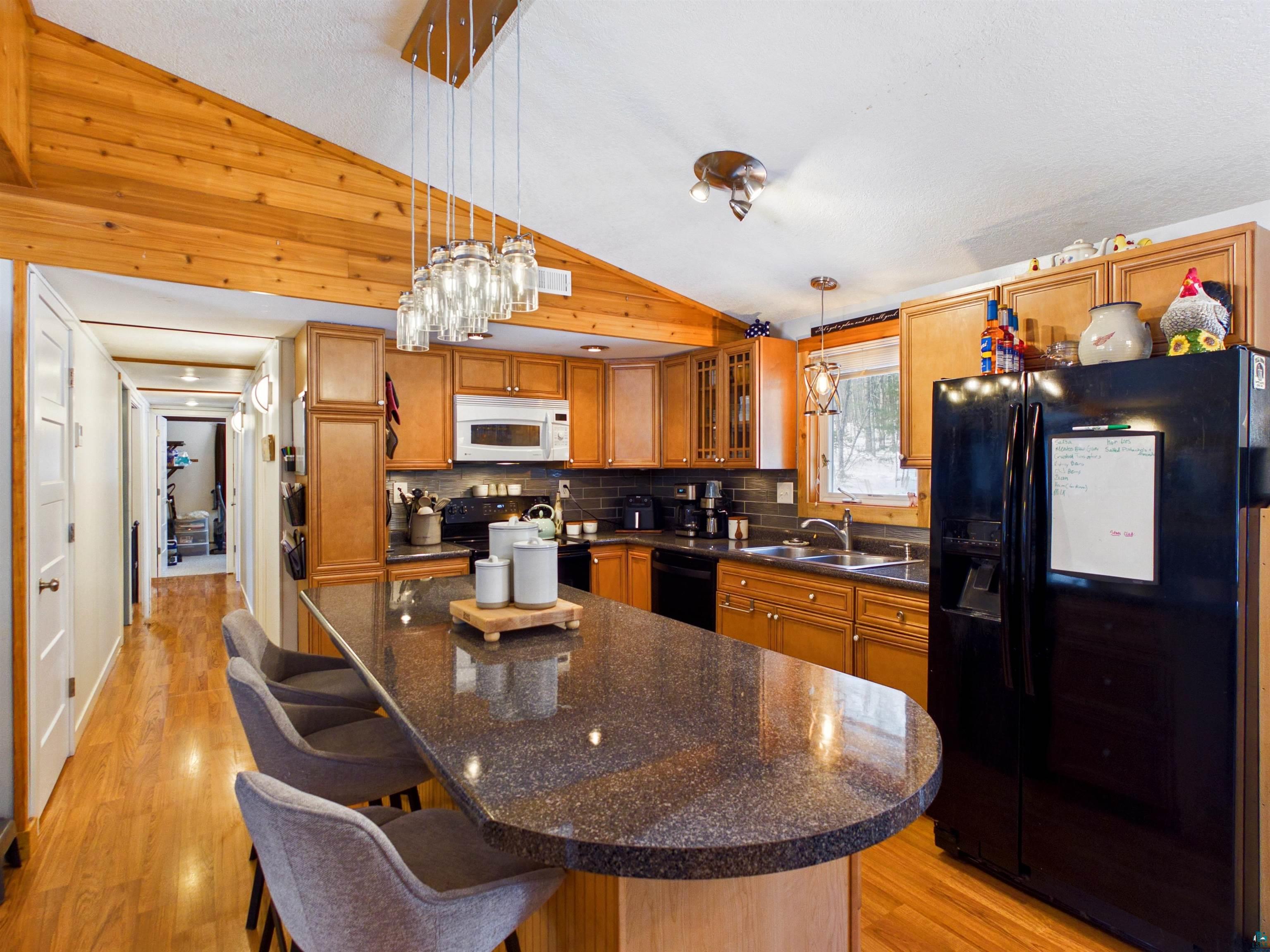 10719 North Oak Ridge Street Hayward, WI 54843 - Photo 16 of 57 Kitchen with vaulted ceiling, black appliances, light wood-type flooring, a kitchen island, and decorative light fixtures