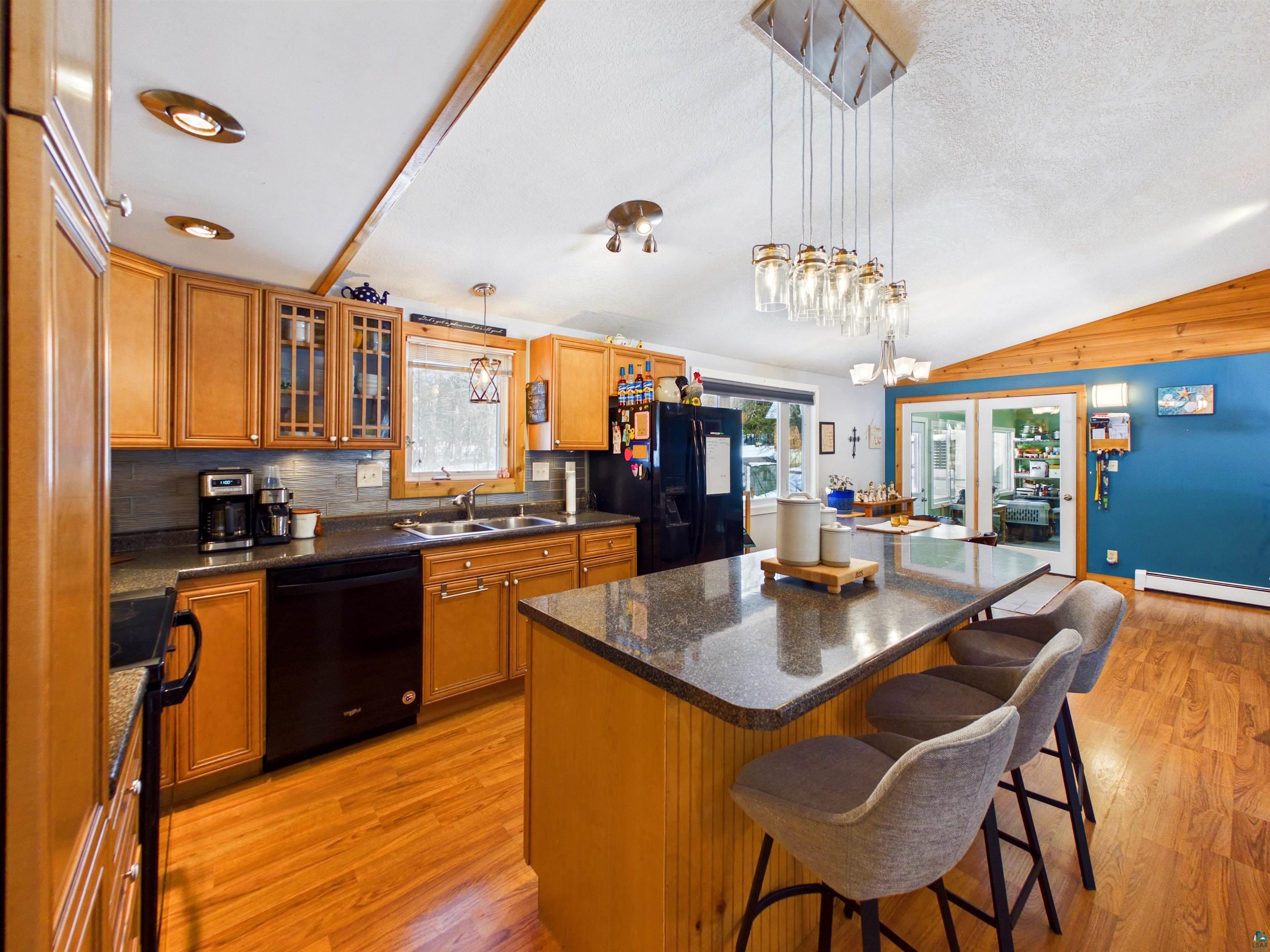10719 North Oak Ridge Street Hayward, WI 54843 - Photo 18 of 57 Kitchen featuring a breakfast bar area, a kitchen island, wood finish cabinets, black appliances, and light wood-style flooring