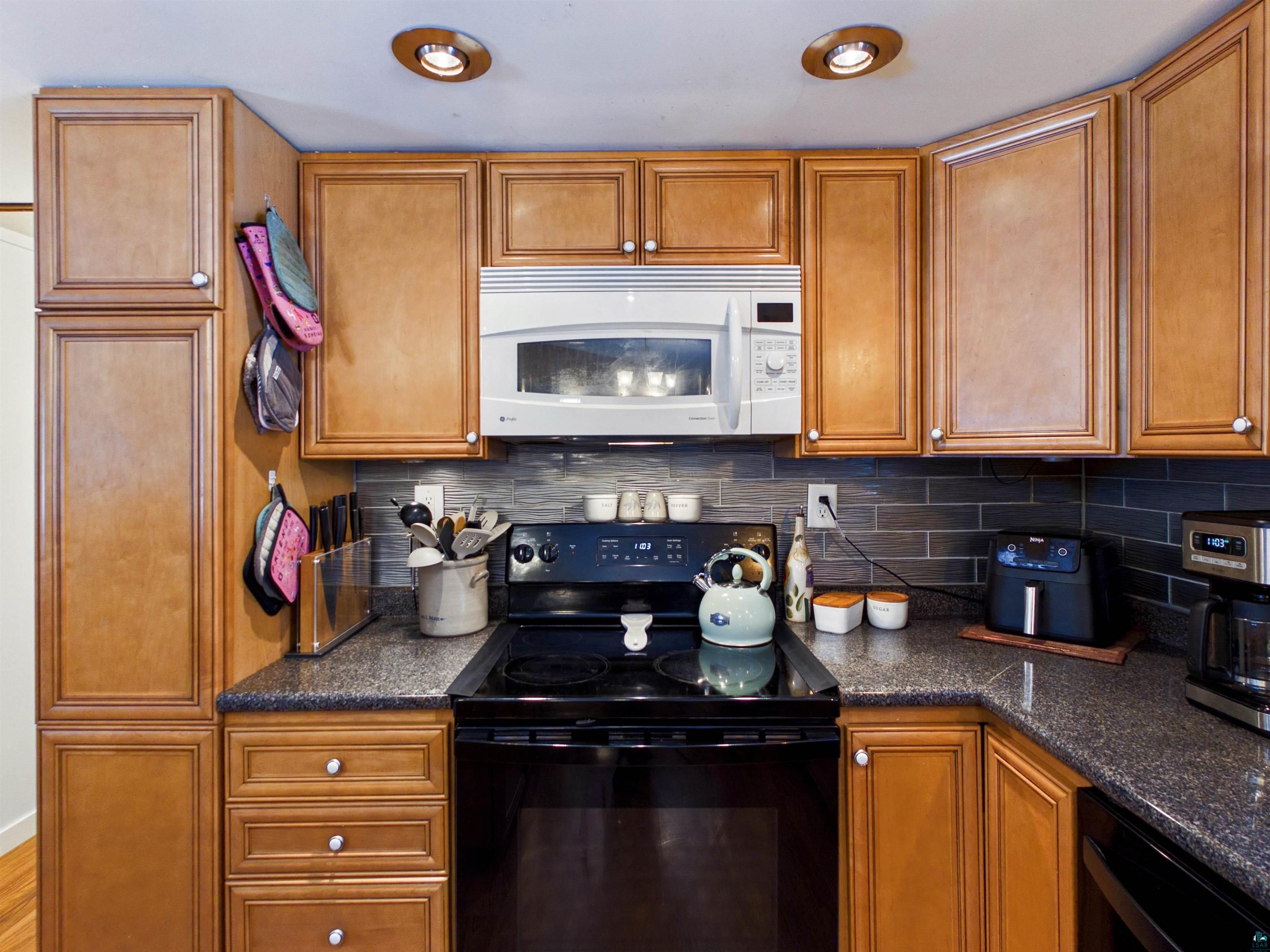 10719 North Oak Ridge Street Hayward, WI 54843 - Photo 22 of 57 Kitchen with black appliances, wood finish cabinetry, and dark stone countertops