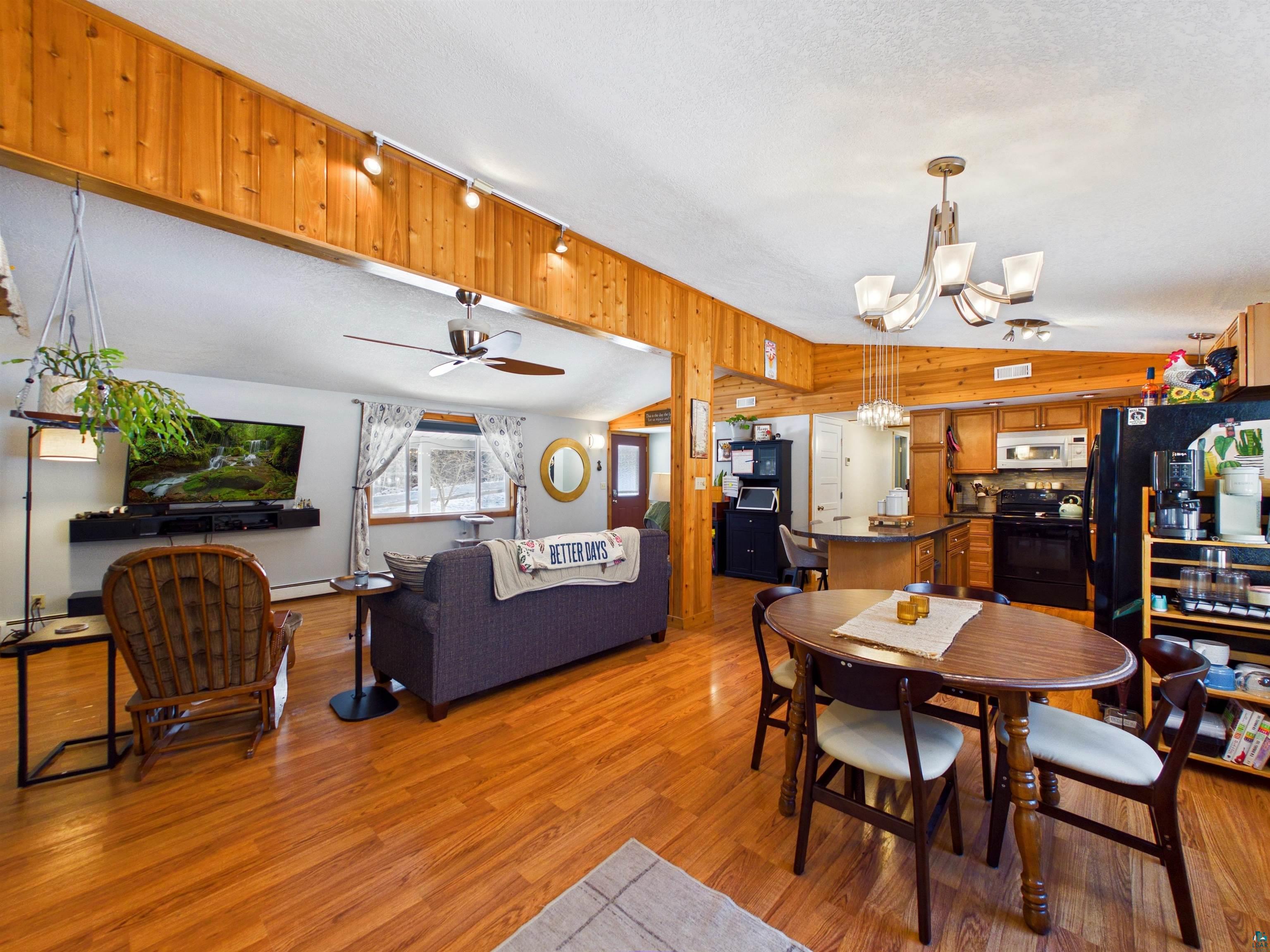 10719 North Oak Ridge Street Hayward, WI 54843 - Photo 24 of 57 Dining room with a ceiling fan, a chandelier, light wood-type flooring, and wood walls