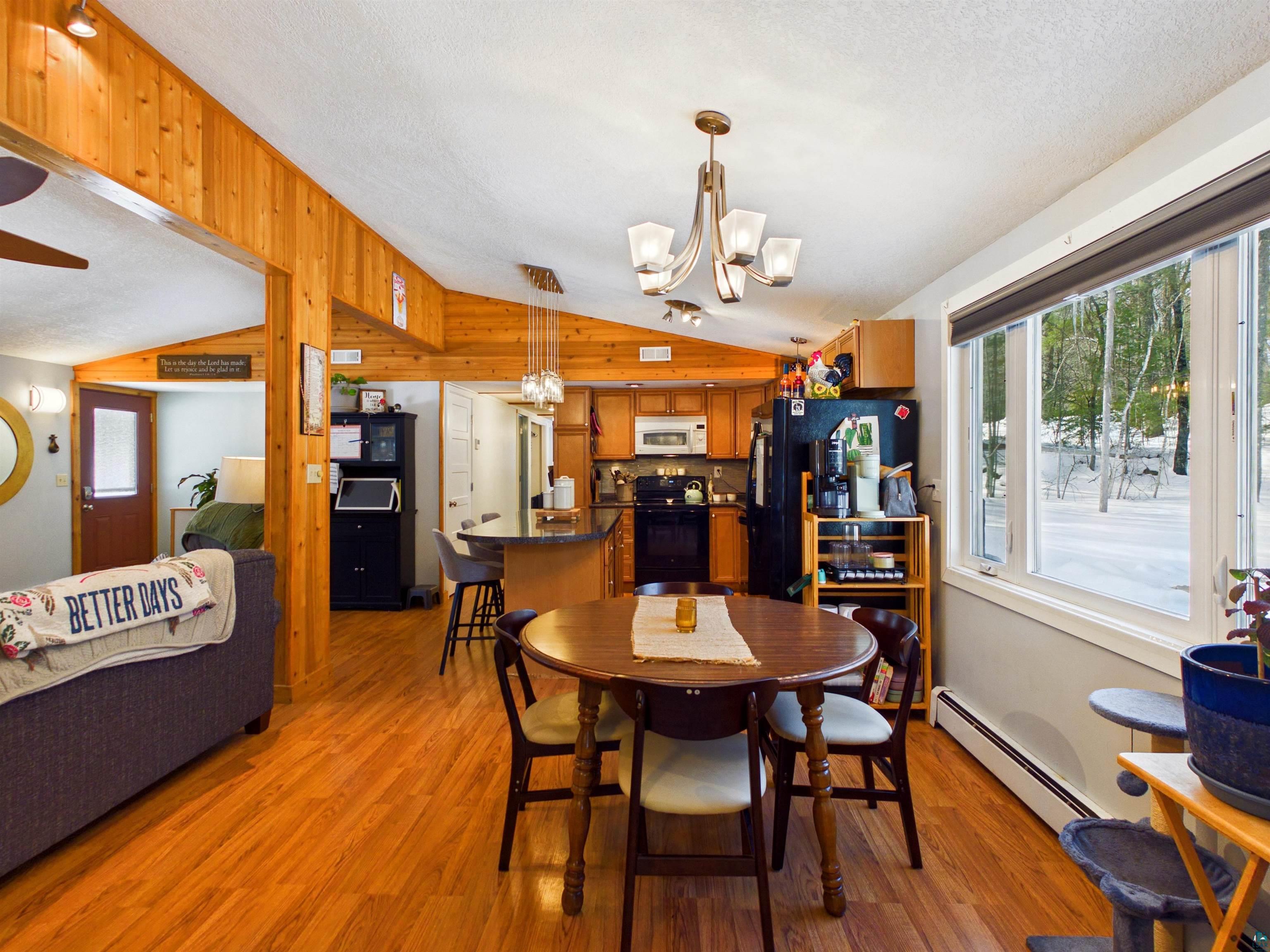 10719 North Oak Ridge Street Hayward, WI 54843 - Photo 25 of 57 Dining area with a baseboard radiator, light wood-style floors, a chandelier, and wooden walls