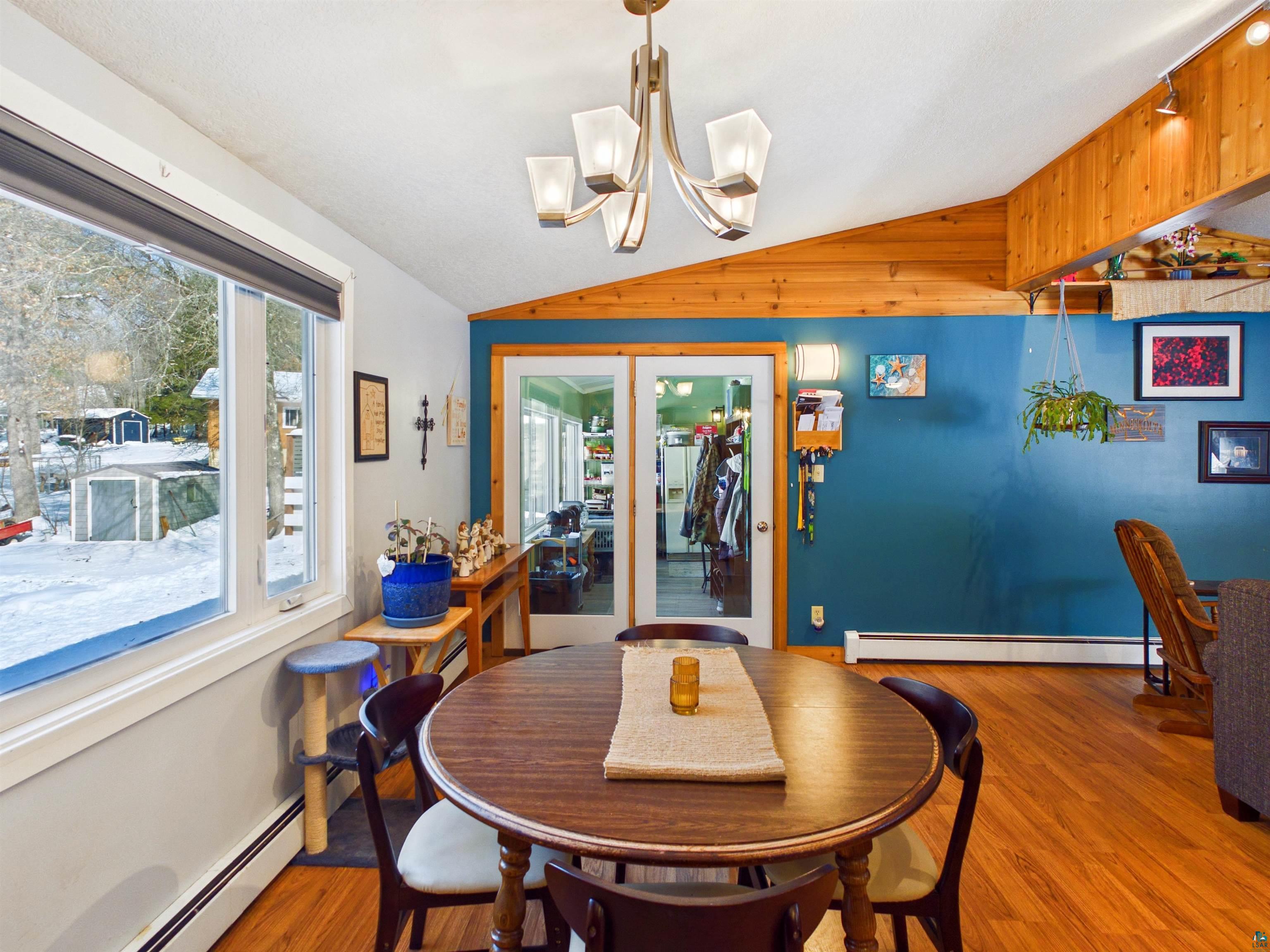 10719 North Oak Ridge Street Hayward, WI 54843 - Photo 27 of 57 Dining room featuring vaulted ceiling, wood finished floors, baseboard heating, and a chandelier