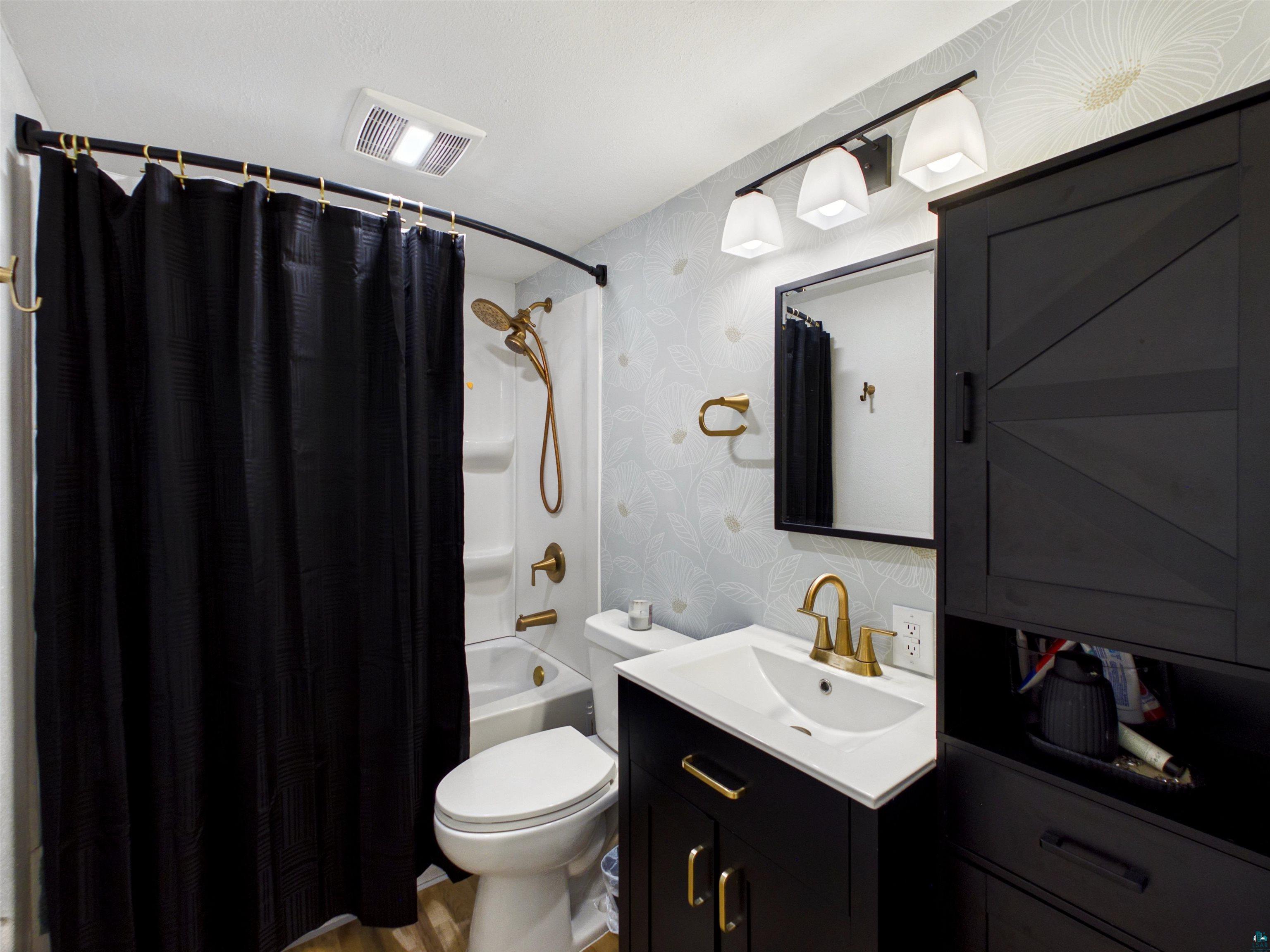 10719 North Oak Ridge Street Hayward, WI 54843 - Photo 33 of 57 Bathroom featuring vanity, wallpapered walls, shower / tub combo with curtain, and light wood finished floors