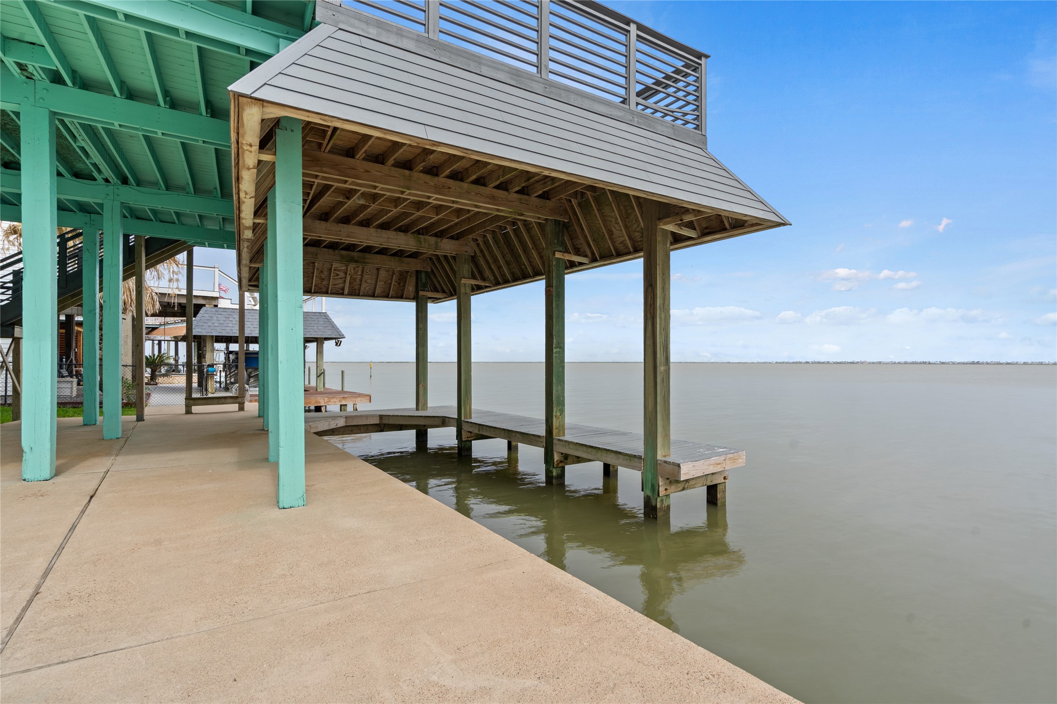 407 Isles End Road Tiki Island, TX 77554 - Photo 33 of 34 wooden roof deck with table and chairs under an umbrella