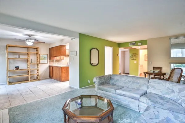 a living room with stainless steel appliances furniture a flat screen tv and a window
