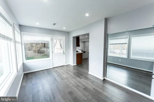 a view of an empty room with window and wooden floor