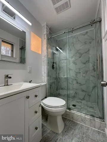 a bathroom with a shower sink mirror and toilet