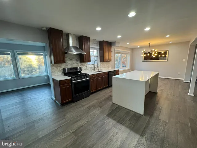 a large kitchen with stainless steel appliances kitchen island granite countertop a stove a sink and a microwave