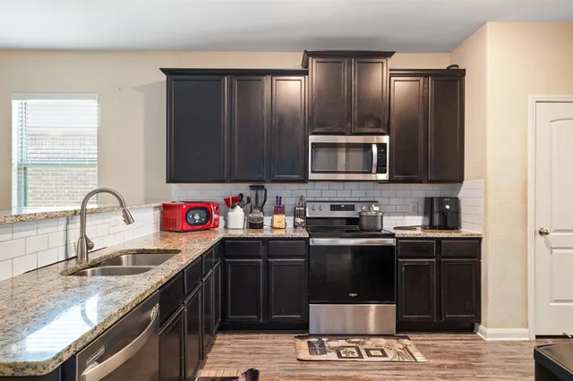 a kitchen with stainless steel appliances granite countertop a sink stove and refrigerator