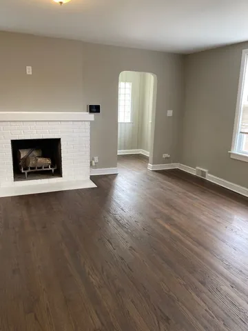 an empty room with wooden floor a fireplace and windows