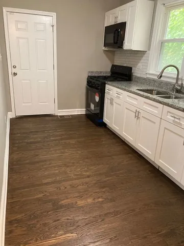 a kitchen with granite countertop white cabinets and sink