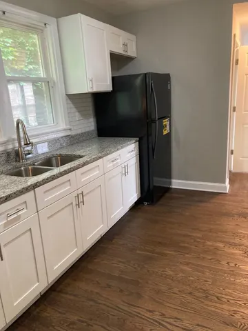 a kitchen with granite countertop white cabinets and refrigerator