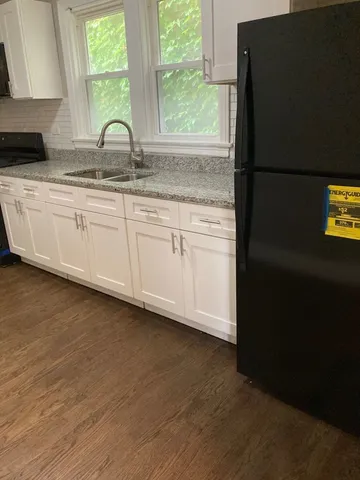a kitchen with granite countertop white cabinets and a refrigerator