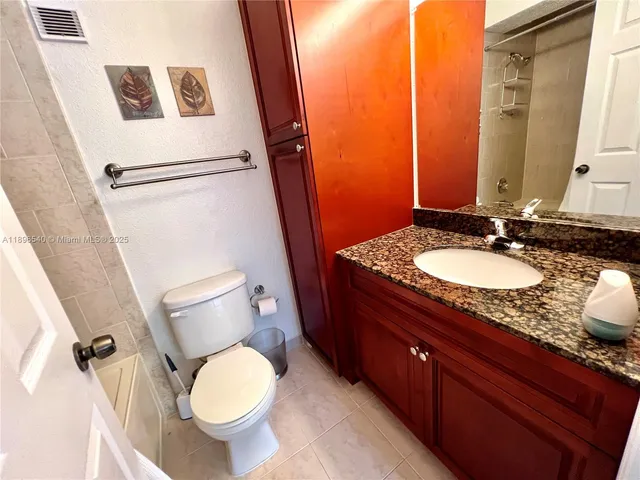 a bathroom with a granite countertop sink toilet and shower