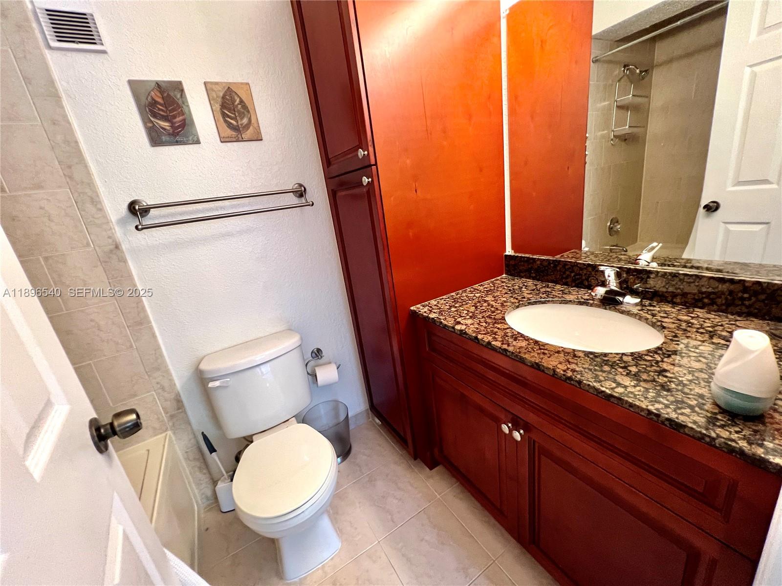 15689 Southwest 106th Lane, Unit 706 Miami, FL 33196 - Photo 16 of 23 a bathroom with a granite countertop sink toilet and shower