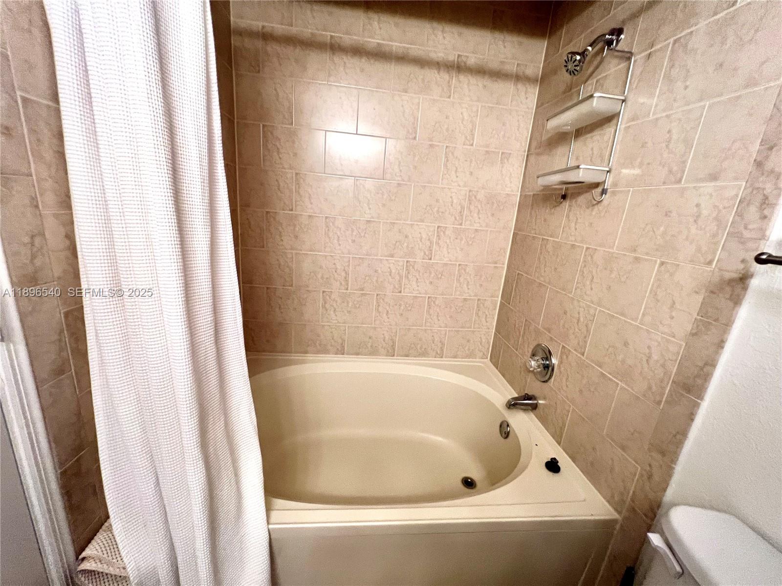 15689 Southwest 106th Lane, Unit 706 Miami, FL 33196 - Photo 17 of 23 a white bath tub and a shower curtain