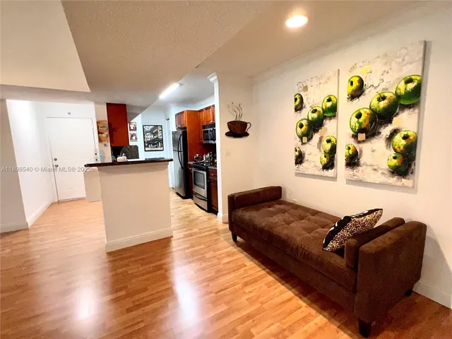 a living room with stainless steel appliances kitchen island granite countertop furniture and a wooden floor