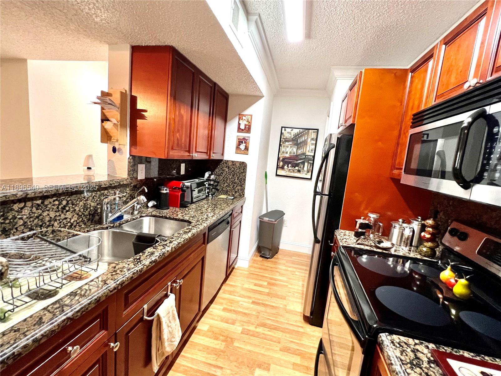 15689 Southwest 106th Lane, Unit 706 Miami, FL 33196 - Photo 9 of 23 a kitchen with stainless steel appliances granite countertop sink stove and cabinets