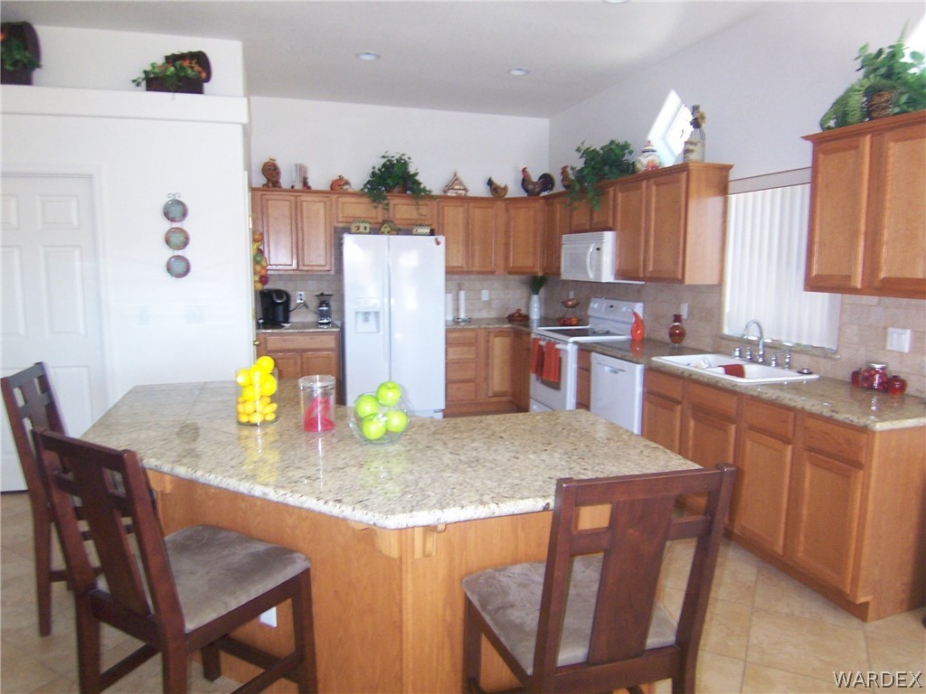 2340 Corwin Road Bullhead City, AZ 86442 - Photo 9 of 38 a kitchen with stainless steel appliances kitchen island granite countertop a table chairs and a refrigerator