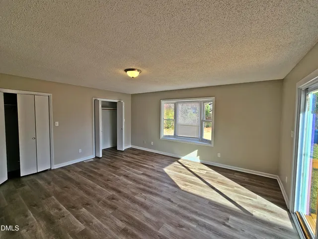 a view of a bedroom with wooden floor and window