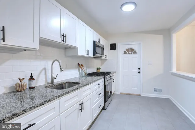 a kitchen with granite countertop a sink a stove and cabinets