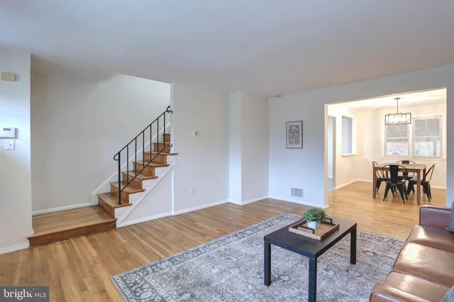 a living room with furniture and a dining table with wooden floor