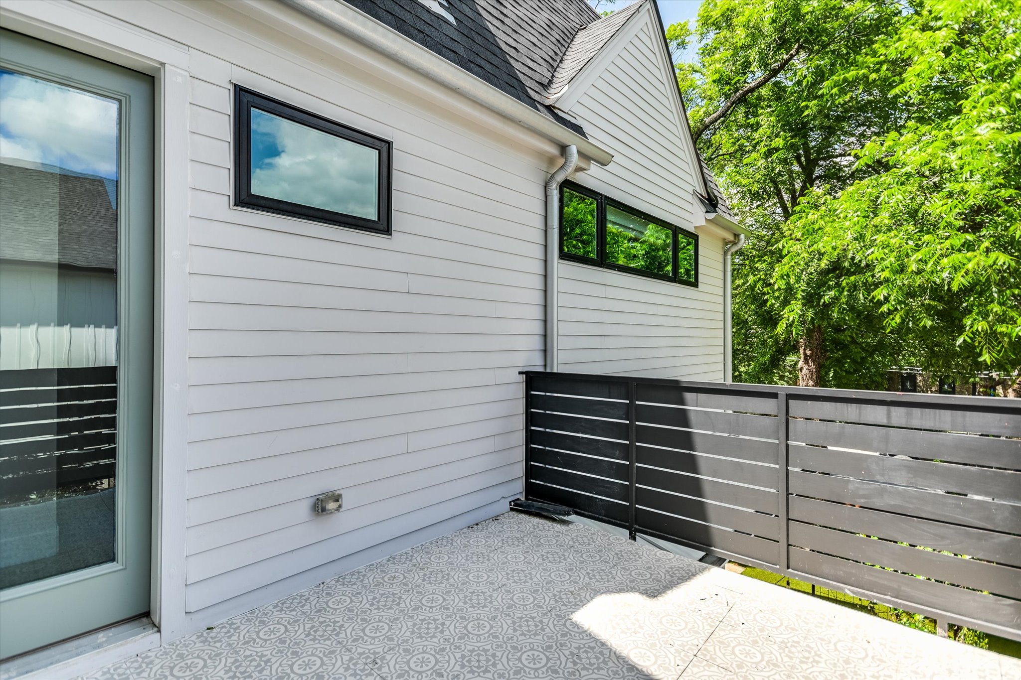 1605 Hether Street Austin, TX 78704 - Photo 21 of 26 Outdoor patio area with patterned concrete flooring, a dark horizontally slatted railing, and white horizontal siding