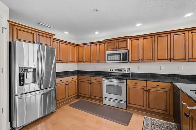 a kitchen with granite countertop stainless steel appliances a refrigerator and cabinets