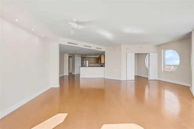 a view of an empty room with window and wooden floor