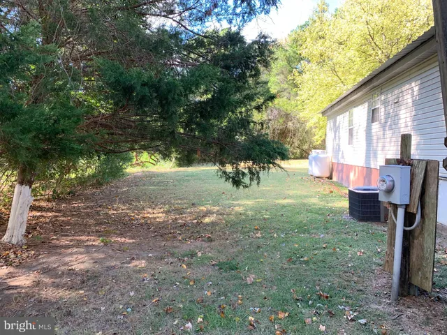 a view of a backyard with table and chairs potted plants and large tree