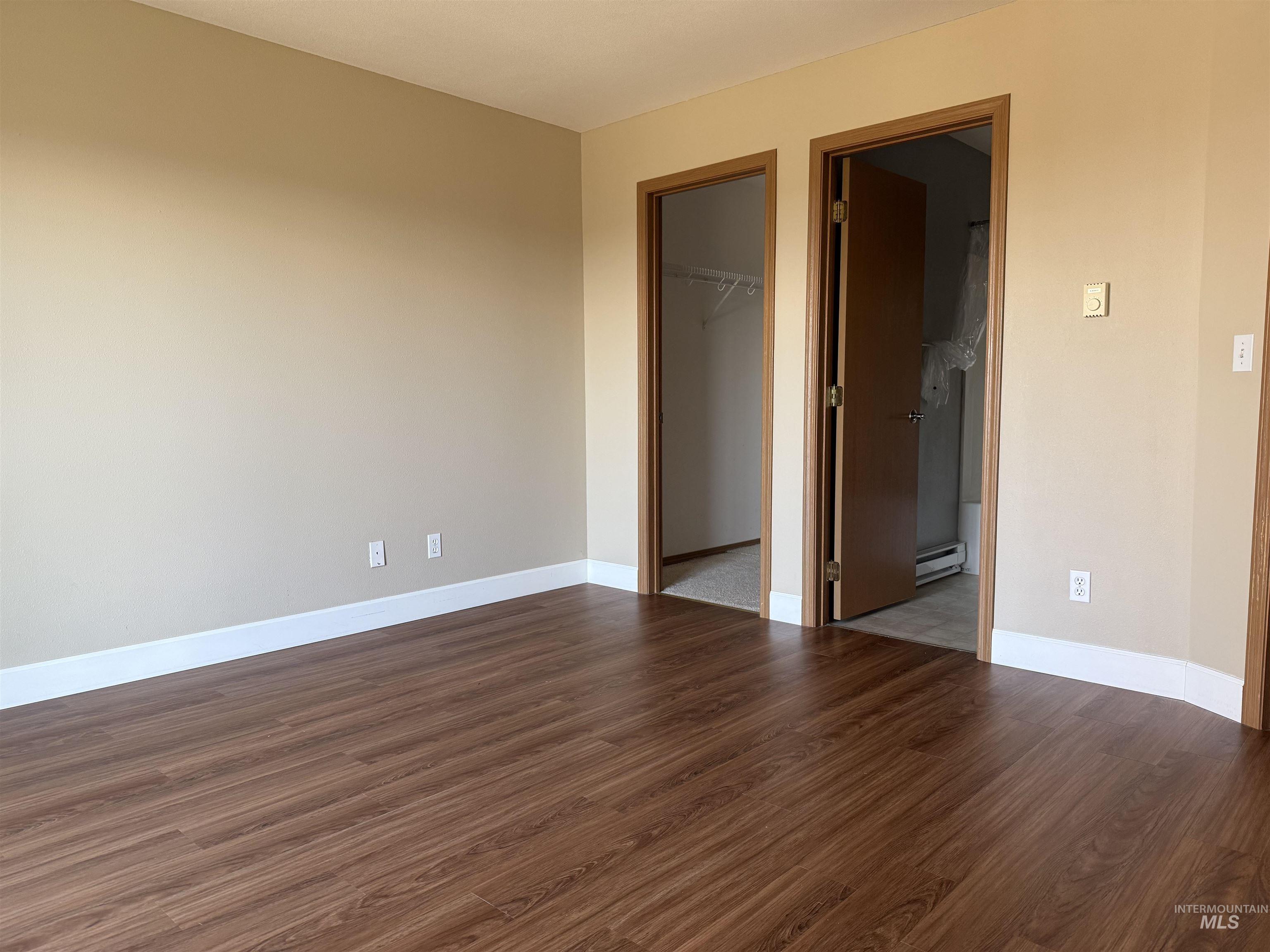 257 Pintail Lane Moscow, ID 83843 - Photo 13 of 28 Unfurnished bedroom with dark wood-style flooring, a walk in closet, ensuite bathroom, and baseboard heating