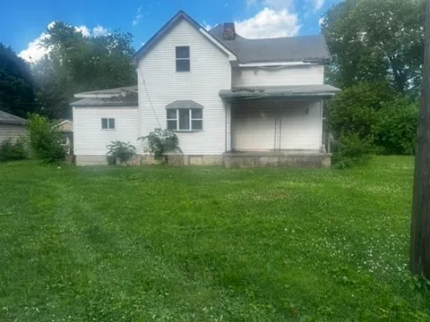 a view of a white house with a big yard and large trees