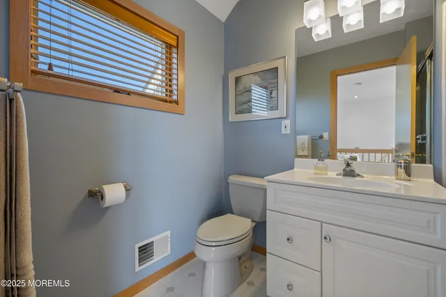 a bathroom with a granite countertop toilet a sink a mirror and a window