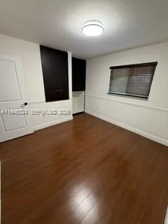 a view of an empty room with kitchen and window